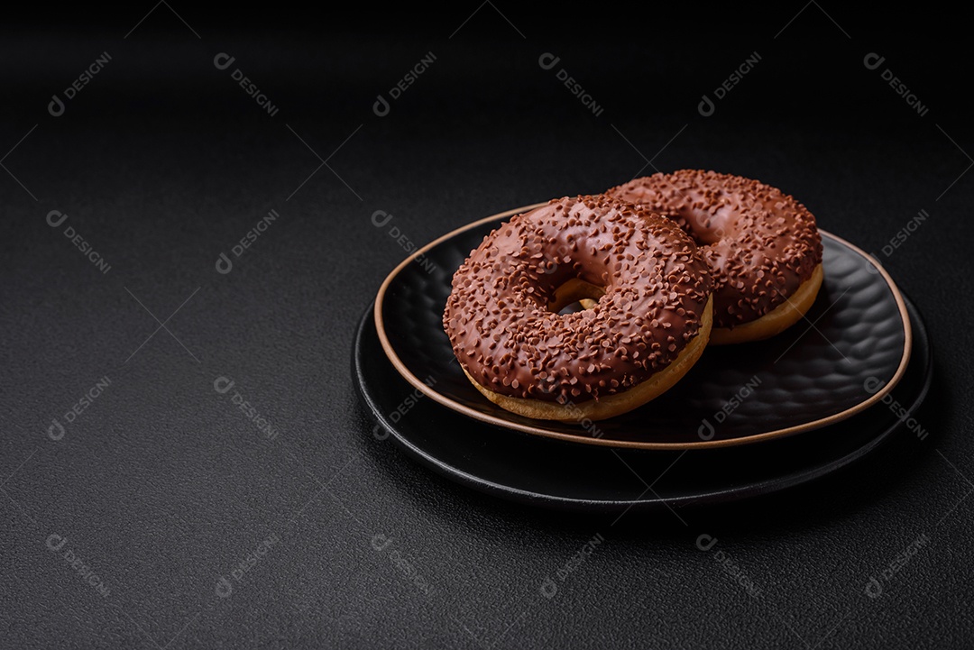 Delicioso donut com cobertura de chocolate polvilhado com pedaços de chocolate sobre um fundo escuro de concreto