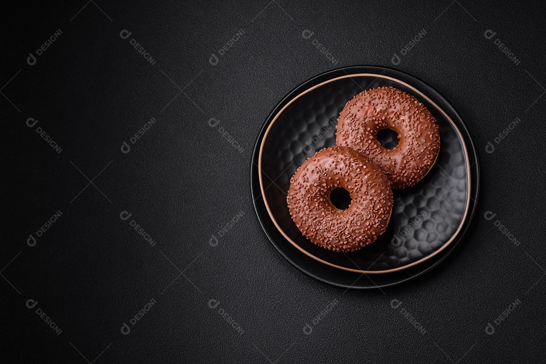 Delicioso donut com cobertura de chocolate polvilhado com pedaços de chocolate sobre um fundo escuro de concreto