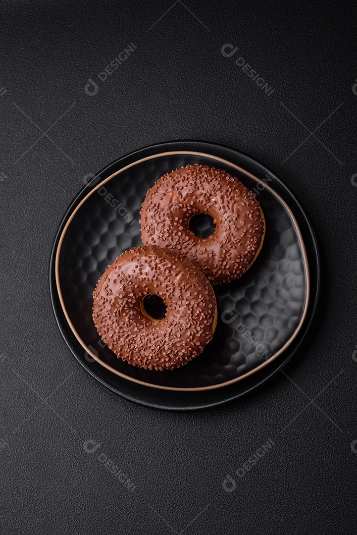 Delicioso donut com cobertura de chocolate polvilhado com pedaços de chocolate sobre um fundo escuro de concreto