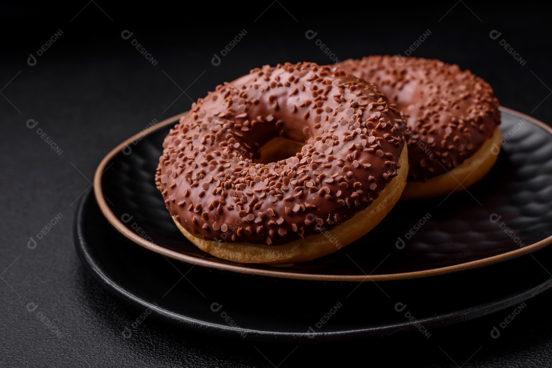Delicioso donut com cobertura de chocolate polvilhado com pedaços de chocolate sobre um fundo escuro de concreto