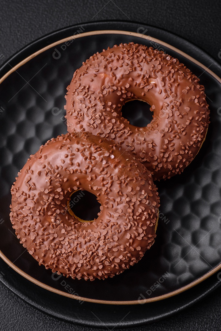 Delicioso donut com cobertura de chocolate polvilhado com pedaços de chocolate sobre um fundo escuro de concreto
