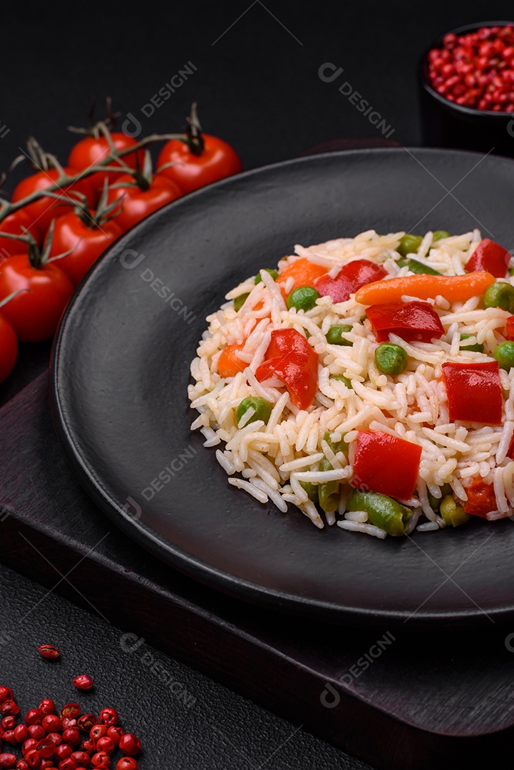 Delicioso arroz cozido com pimentão, ervilha, feijão de espargos e cenoura sobre um fundo de concreto texturizado