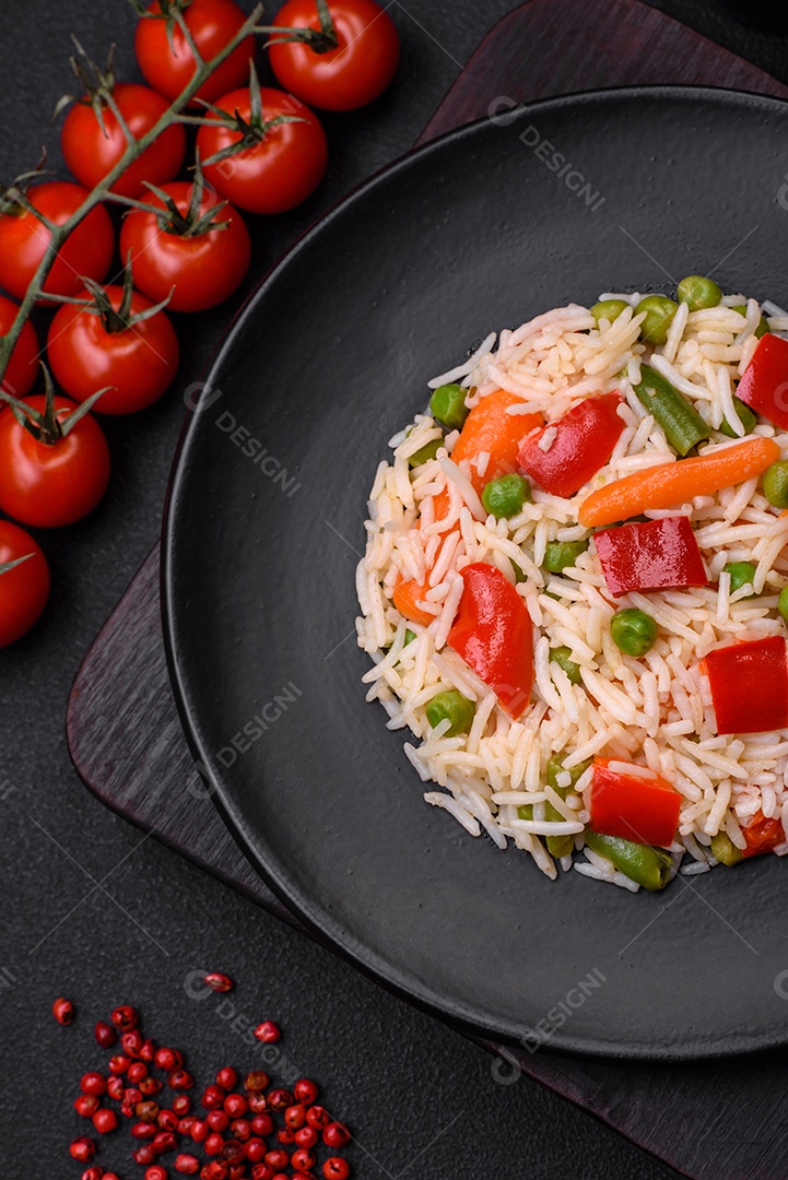 Delicioso arroz cozido com pimentão, ervilha, feijão de espargos e cenoura sobre um fundo de concreto texturizado