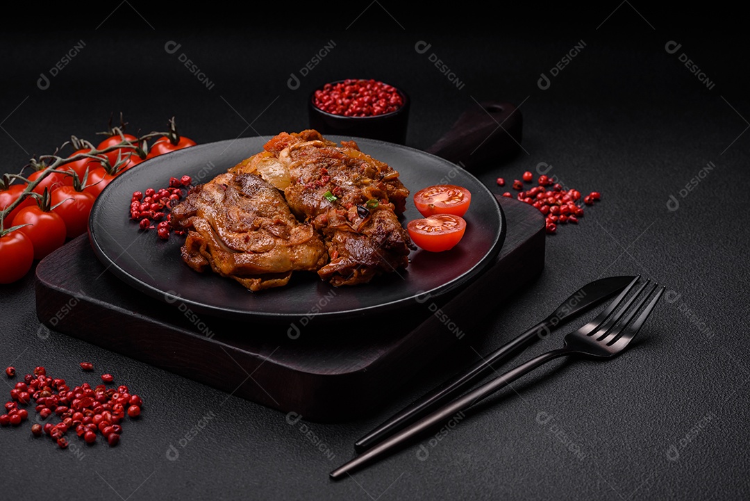 Delicioso frango frito em molho com cebola, sal, especiarias e ervas sobre um fundo escuro de concreto