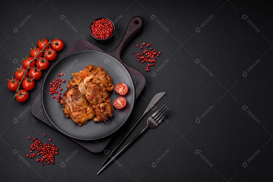 Delicioso frango frito em molho com cebola, sal, especiarias e ervas sobre um fundo escuro de concreto