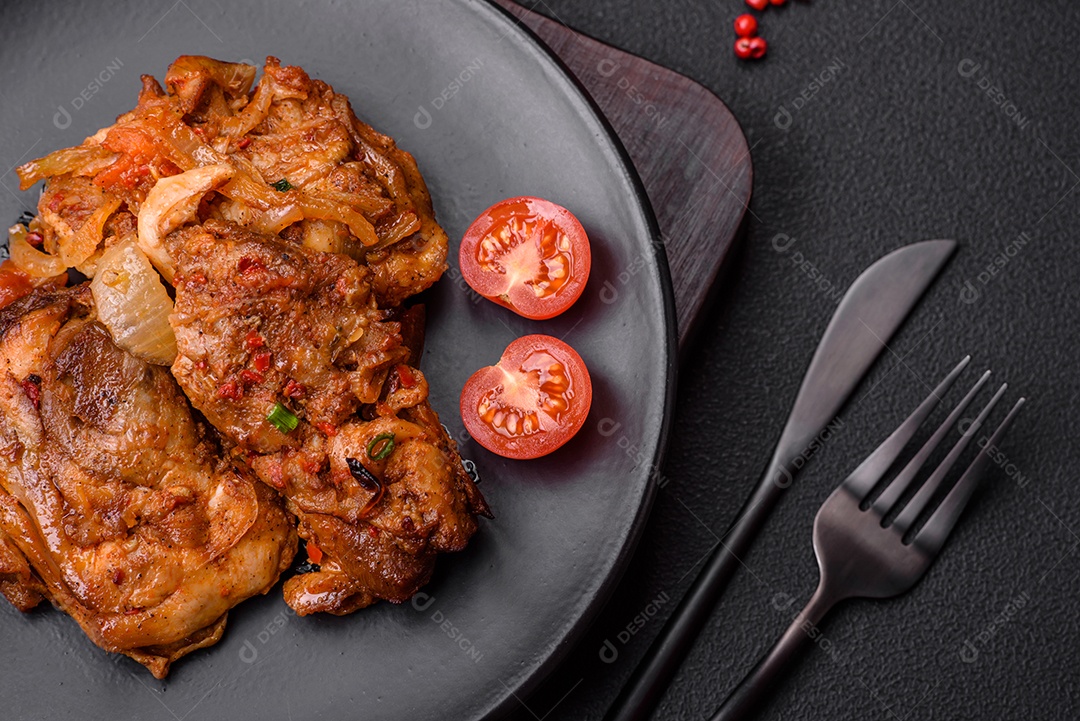 Delicioso frango frito em molho com cebola, sal, especiarias e ervas sobre um fundo escuro de concreto
