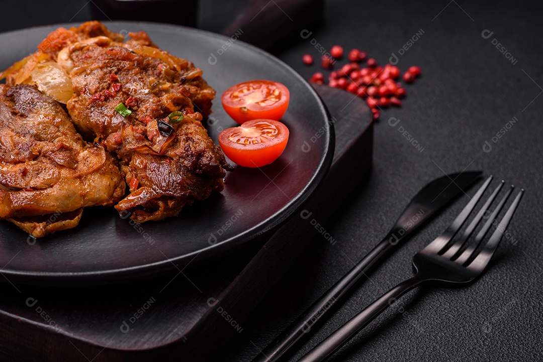 Delicioso frango frito em molho com cebola, sal, especiarias e ervas sobre um fundo escuro de concreto