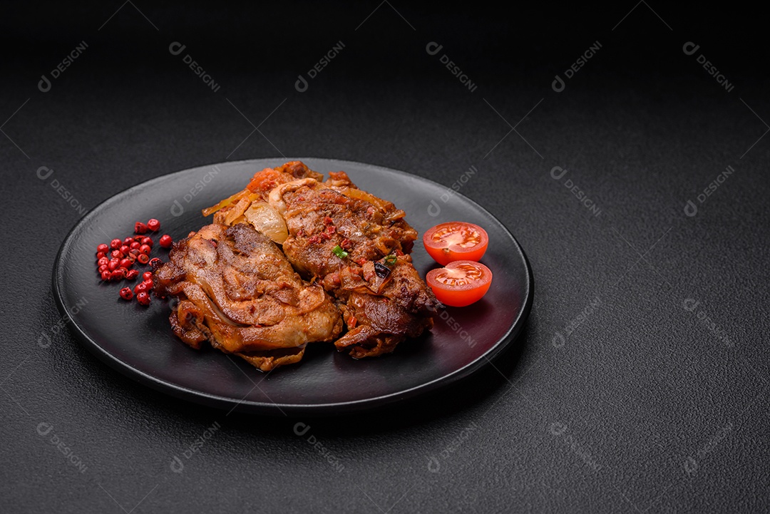 Delicioso frango frito em molho com cebola, sal, especiarias e ervas sobre um fundo escuro de concreto