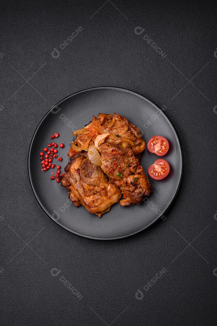 Delicioso frango frito em molho com cebola, sal, especiarias e ervas sobre um fundo escuro de concreto