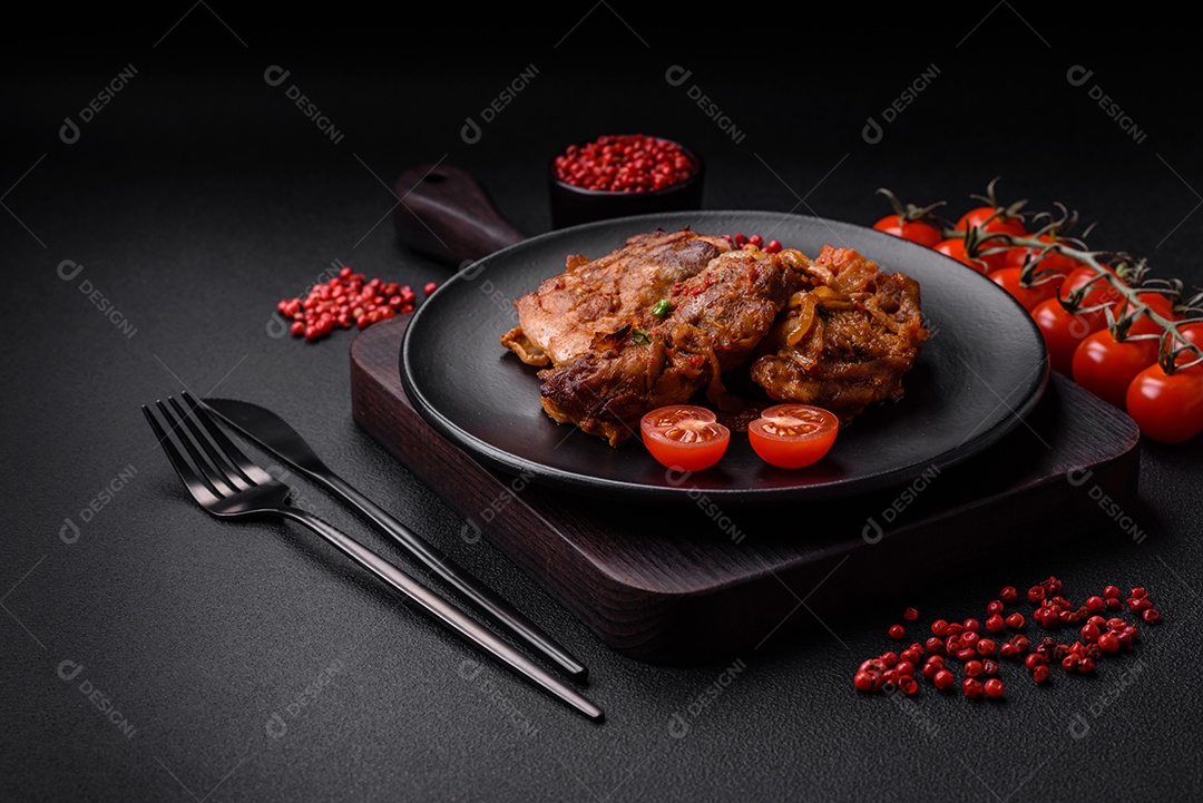 Delicioso frango frito em molho com cebola, sal, especiarias e ervas sobre um fundo escuro de concreto