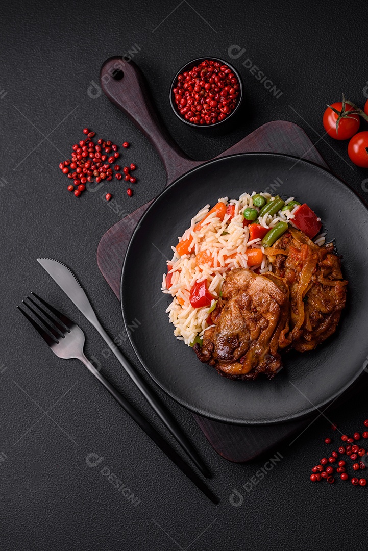 Delicioso arroz cozido com pimentão, ervilha, feijão de espargos e cenoura e frango frito sobre fundo de concreto texturizado