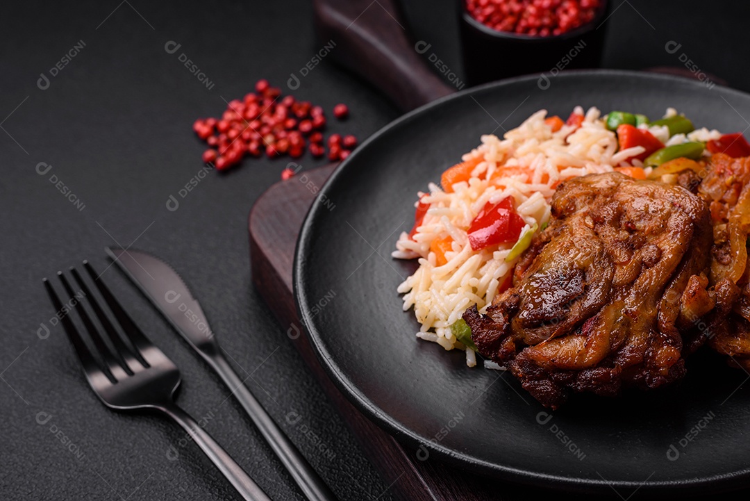 Delicioso arroz cozido com pimentão, ervilha, feijão de espargos e cenoura e frango frito sobre fundo de concreto texturizado
