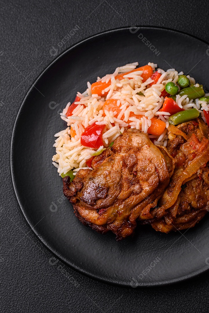 Delicioso arroz cozido com pimentão, ervilha, feijão de espargos e cenoura e frango frito sobre fundo de concreto texturizado