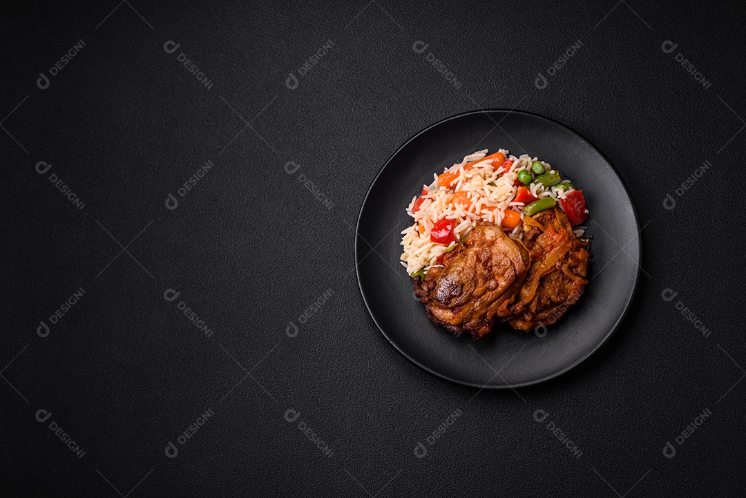Delicioso arroz cozido com pimentão, ervilha, feijão de espargos e cenoura e frango frito sobre fundo de concreto texturizado