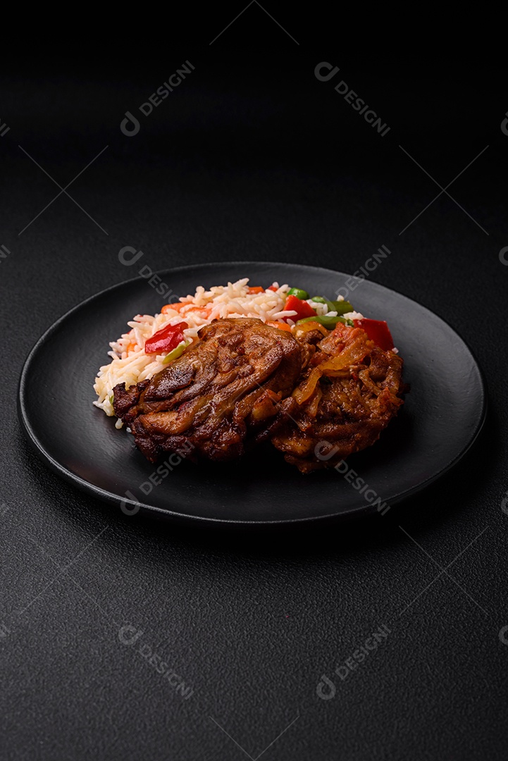 Delicioso arroz cozido com pimentão, ervilha, feijão de espargos e cenoura e frango frito sobre fundo de concreto texturizado