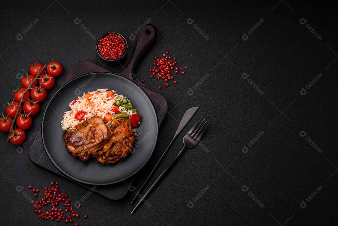 Delicioso arroz cozido com pimentão, ervilha, feijão de espargos e cenoura e frango frito sobre fundo de concreto texturizado