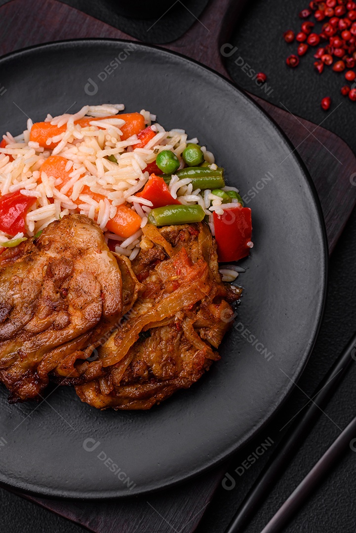 Delicioso arroz cozido com pimentão, ervilha, feijão de espargos e cenoura e frango frito sobre fundo de concreto texturizado