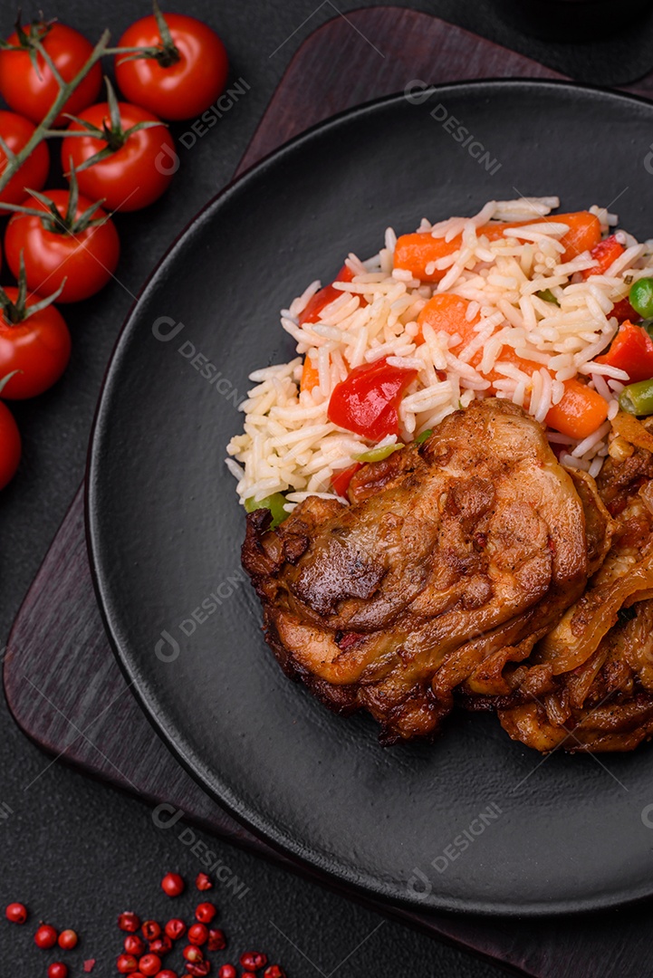 Delicioso arroz cozido com pimentão, ervilha, feijão de espargos e cenoura e frango frito sobre fundo de concreto texturizado