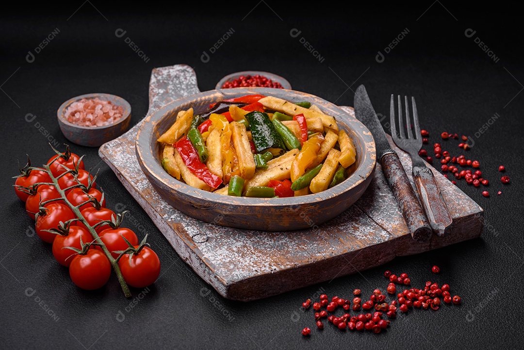 Deliciosas batatas fritas com pimentão, feijão de espargos, sal e especiarias em um prato sobre um fundo escuro de concreto