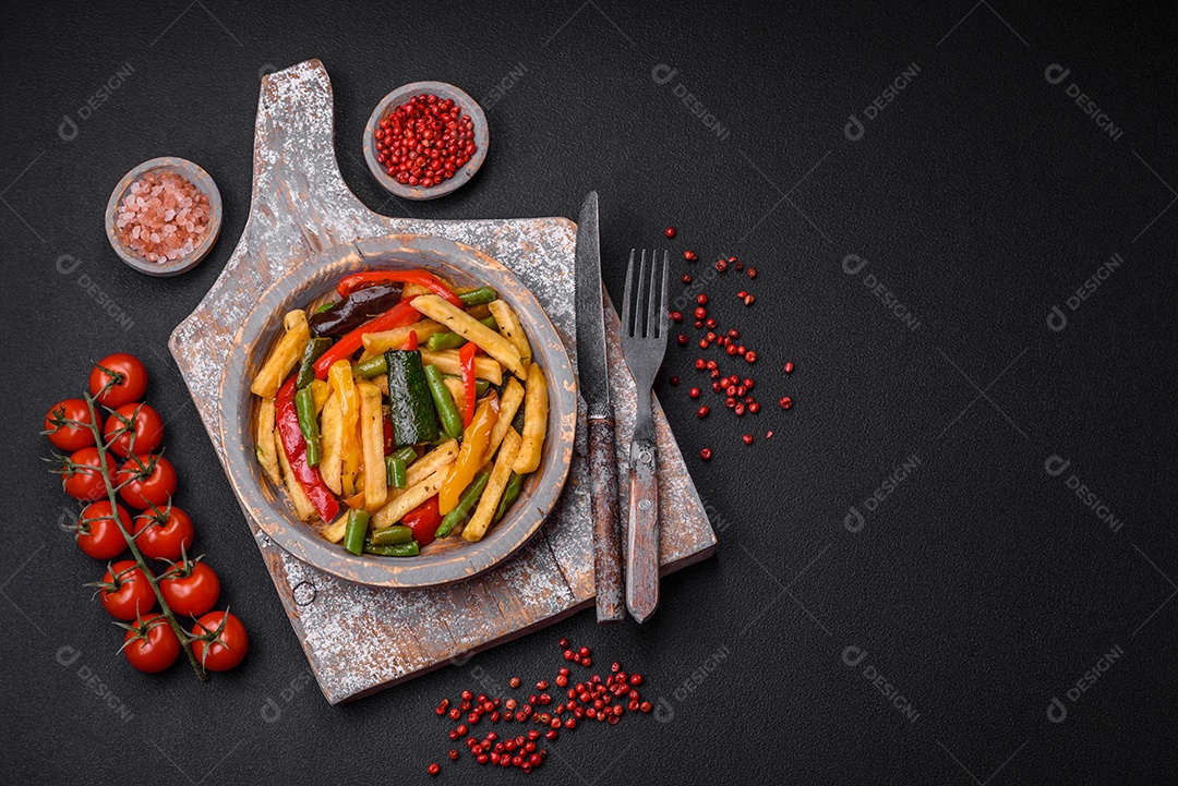 Deliciosas batatas fritas com pimentão, feijão de espargos, sal e especiarias em um prato sobre um fundo escuro de concreto