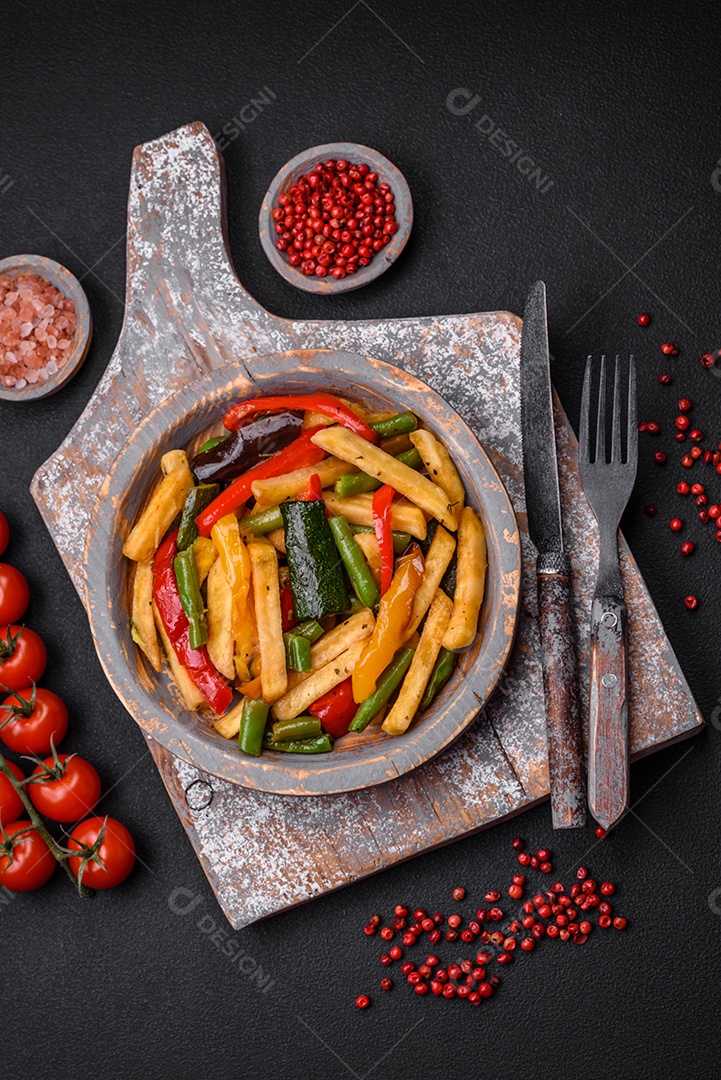 Deliciosas batatas fritas com pimentão, feijão de espargos, sal e especiarias em um prato sobre um fundo escuro de concreto