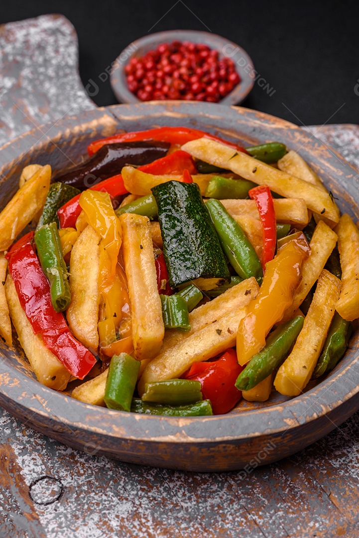 Deliciosas batatas fritas com pimentão, feijão de espargos, sal e especiarias em um prato sobre um fundo escuro de concreto