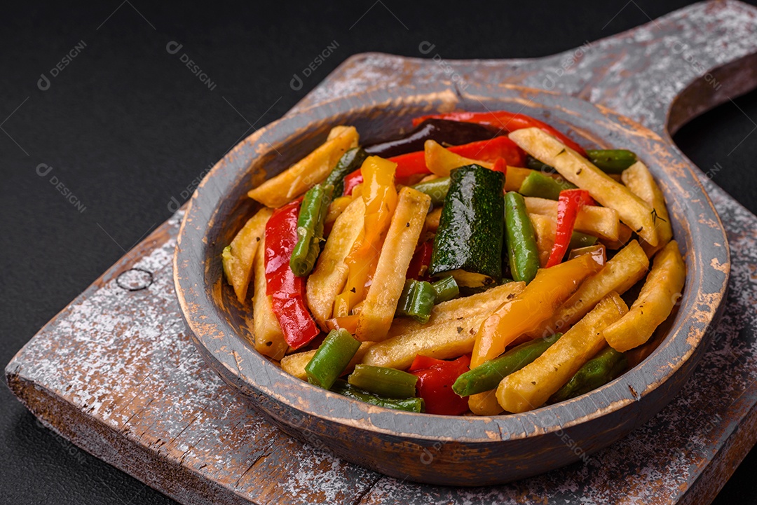 Deliciosas batatas fritas com pimentão, feijão de espargos, sal e especiarias em um prato sobre um fundo escuro de concreto