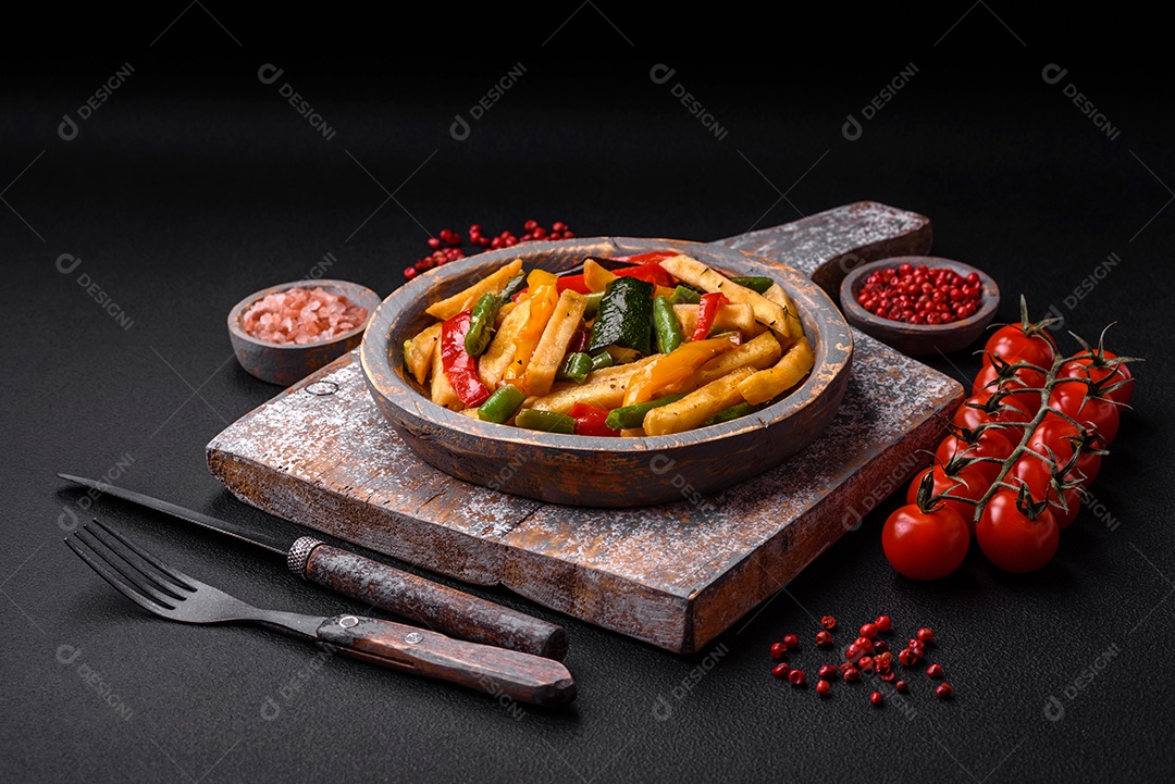 Deliciosas batatas fritas com pimentão, feijão de espargos, sal e especiarias em um prato sobre um fundo escuro de concreto