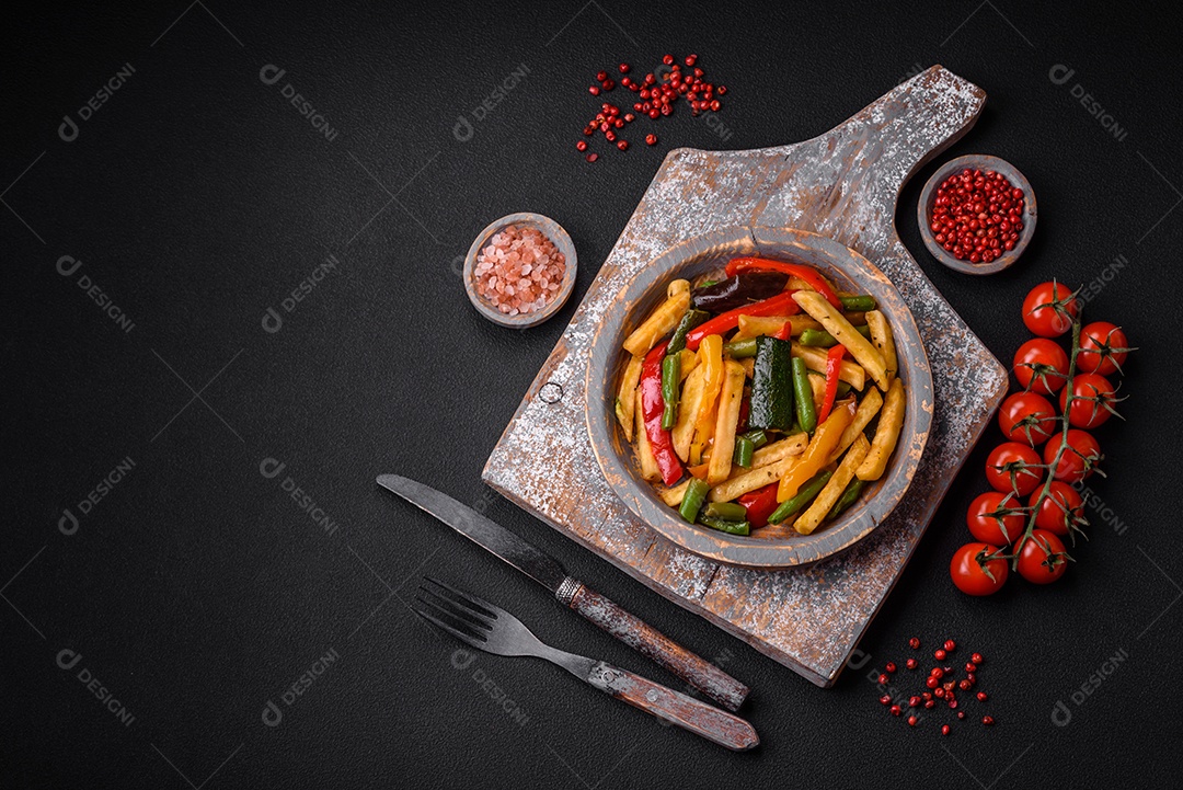 Deliciosas batatas fritas com pimentão, feijão de espargos, sal e especiarias em um prato sobre um fundo escuro de concreto