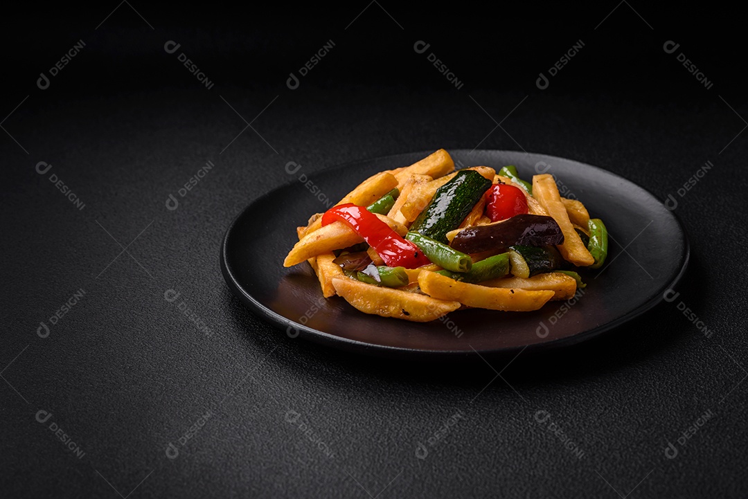 Deliciosas batatas fritas com pimentão, feijão de espargos, sal e especiarias em um prato sobre um fundo escuro de concreto