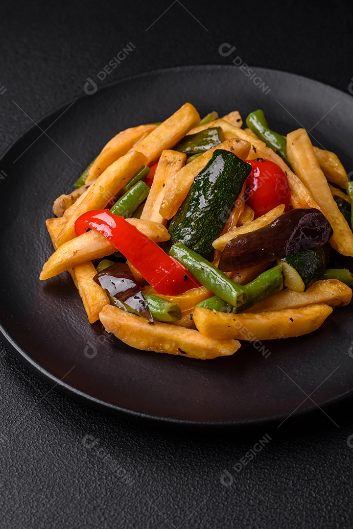 Deliciosas batatas fritas com pimentão, feijão de espargos, sal e especiarias em um prato sobre um fundo escuro de concreto