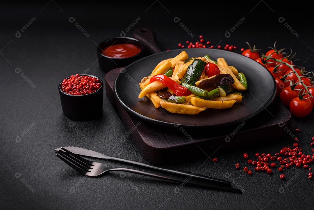 Deliciosas batatas fritas com pimentão, feijão de espargos, sal e especiarias em um prato sobre um fundo escuro de concreto