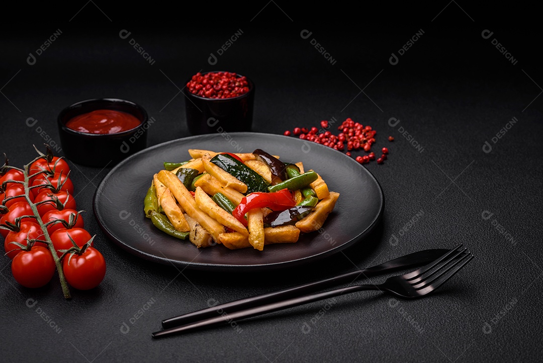 Deliciosas batatas fritas com pimentão, feijão de espargos, sal e especiarias em um prato sobre um fundo escuro de concreto