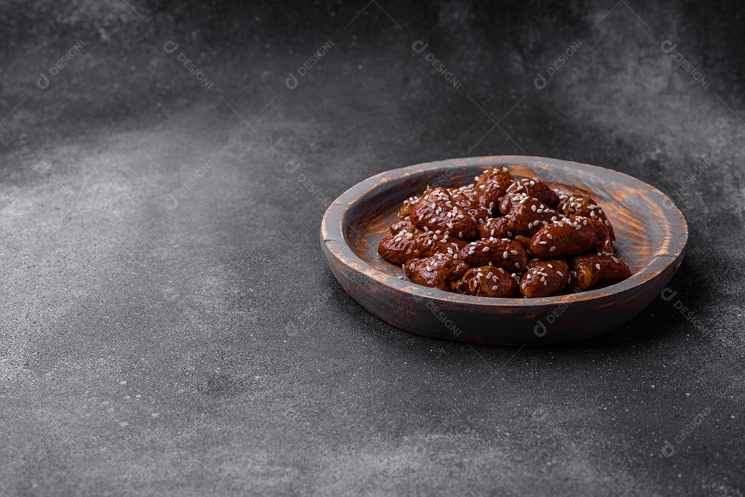 Corações de frango fritos em molho de soja com sal e especiarias em um prato sobre um fundo de concreto texturizado