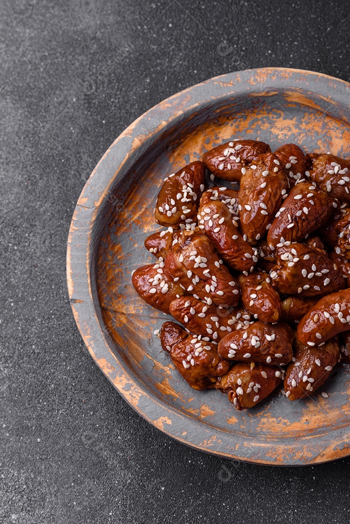 Corações de frango fritos em molho de soja com sal e especiarias em um prato sobre um fundo de concreto texturizado