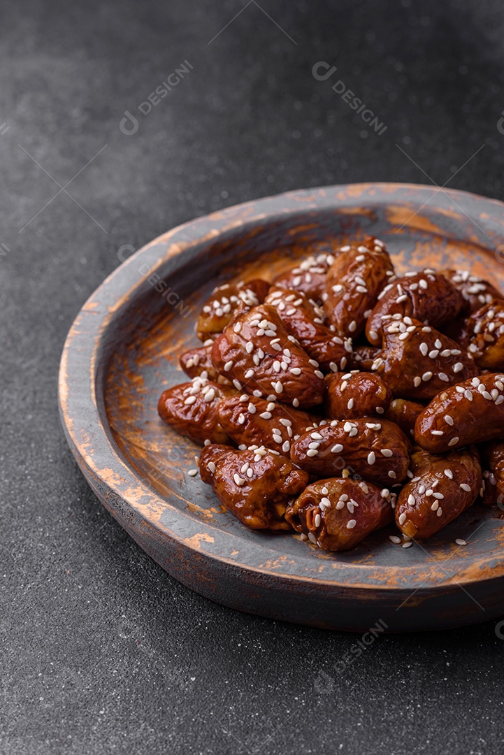 Corações de frango fritos em molho de soja com sal e especiarias em um prato sobre um fundo de concreto texturizado