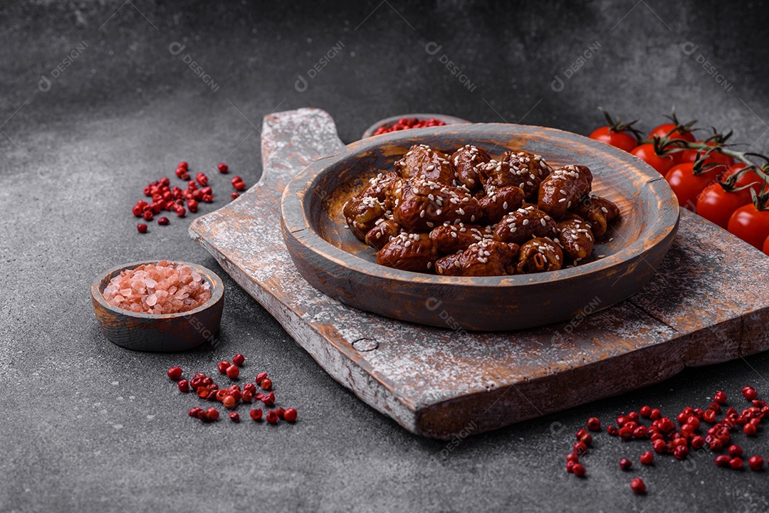 Corações de frango fritos em molho de soja com sal e especiarias em um prato sobre um fundo de concreto texturizado