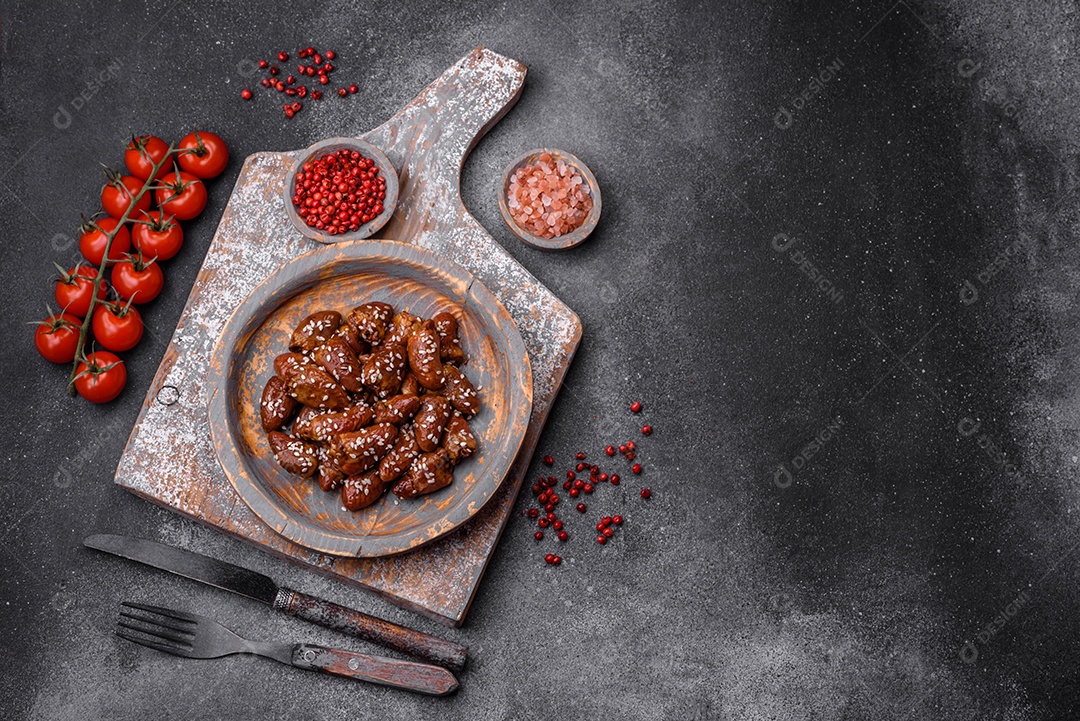 Corações de frango fritos em molho de soja com sal e especiarias em um prato sobre um fundo de concreto texturizado