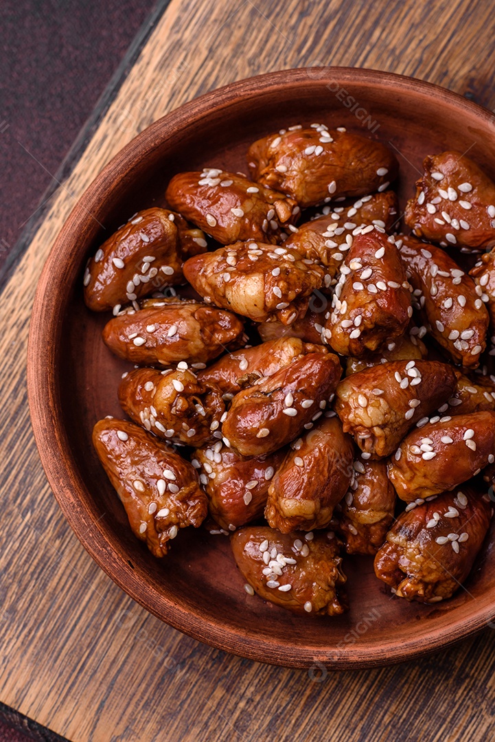 Corações de frango fritos em molho de soja com sal e especiarias em um prato sobre um fundo de concreto texturizado