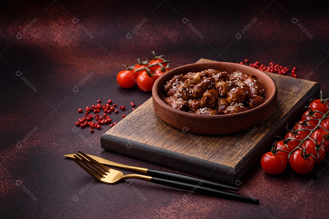 Corações de frango fritos em molho de soja com sal e especiarias em um prato sobre um fundo de concreto texturizado