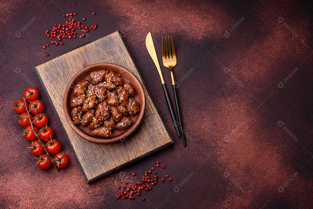 Corações de frango fritos em molho de soja com sal e especiarias em um prato sobre um fundo de concreto texturizado