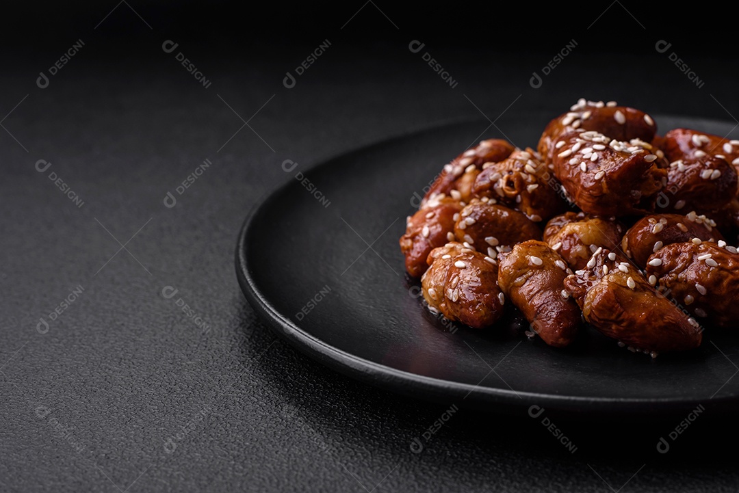 Corações de frango fritos em molho de soja com sal e especiarias em um prato sobre um fundo de concreto texturizado