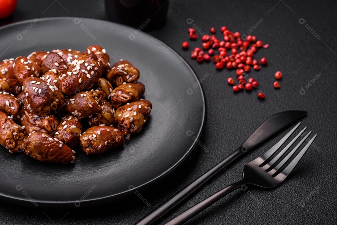 Corações de frango fritos em molho de soja com sal e especiarias em um prato sobre um fundo de concreto texturizado