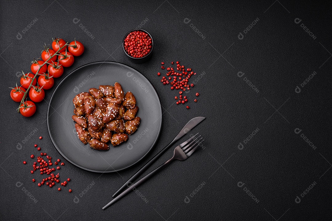 Corações de frango fritos em molho de soja com sal e especiarias em um prato sobre um fundo de concreto texturizado