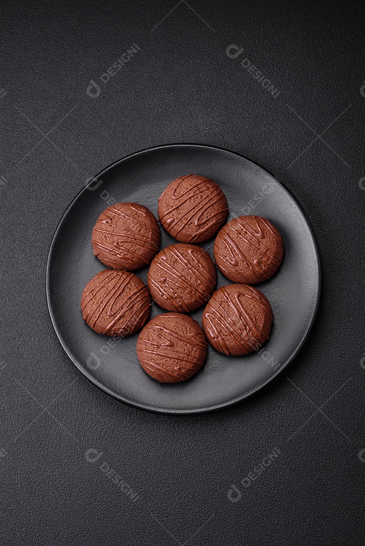 Deliciosos biscoitos de chocolate doce em uma placa de cerâmica preta sobre um fundo escuro de concreto