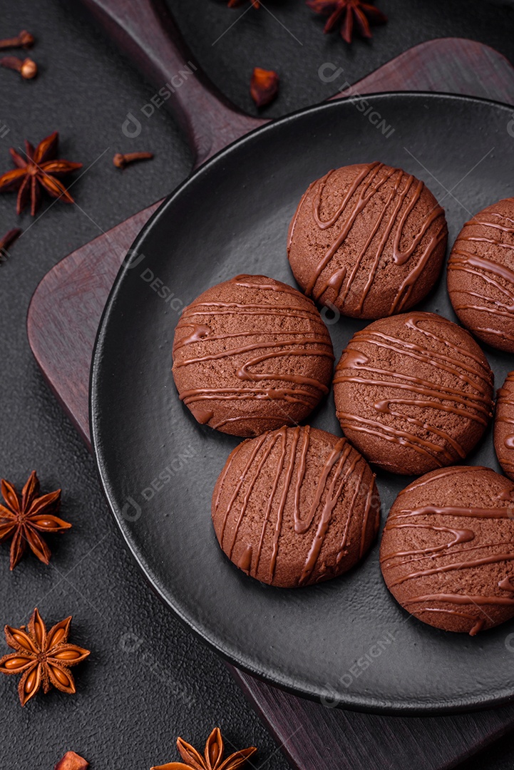 Deliciosos biscoitos de chocolate doce em uma placa de cerâmica preta sobre um fundo escuro de concreto