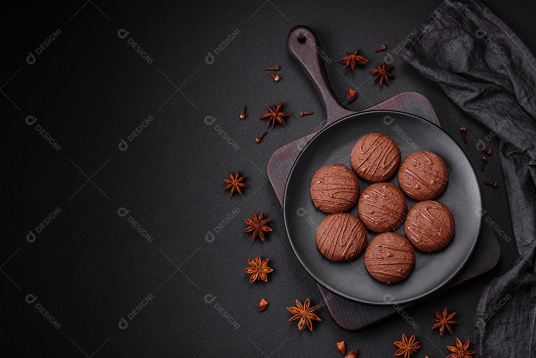 Deliciosos biscoitos de chocolate doce em uma placa de cerâmica preta sobre um fundo escuro de concreto