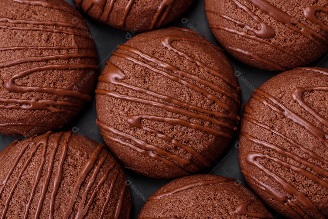 Deliciosos biscoitos de chocolate doce em uma placa de cerâmica preta sobre um fundo escuro de concreto