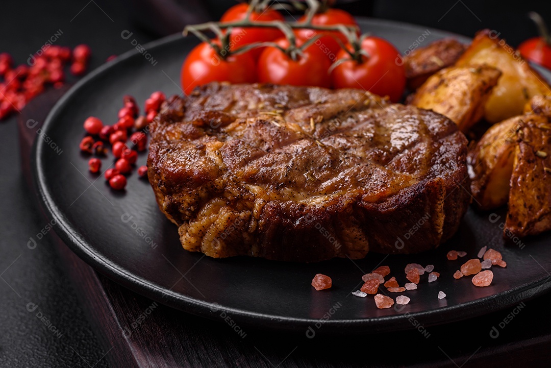 Delicioso bife com sal, especiarias e ervas em uma placa cerâmica sobre um fundo escuro de concreto