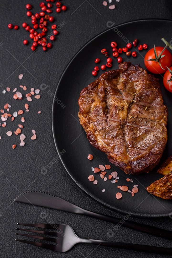 Delicioso bife com sal, especiarias e ervas em uma placa cerâmica sobre um fundo escuro de concreto
